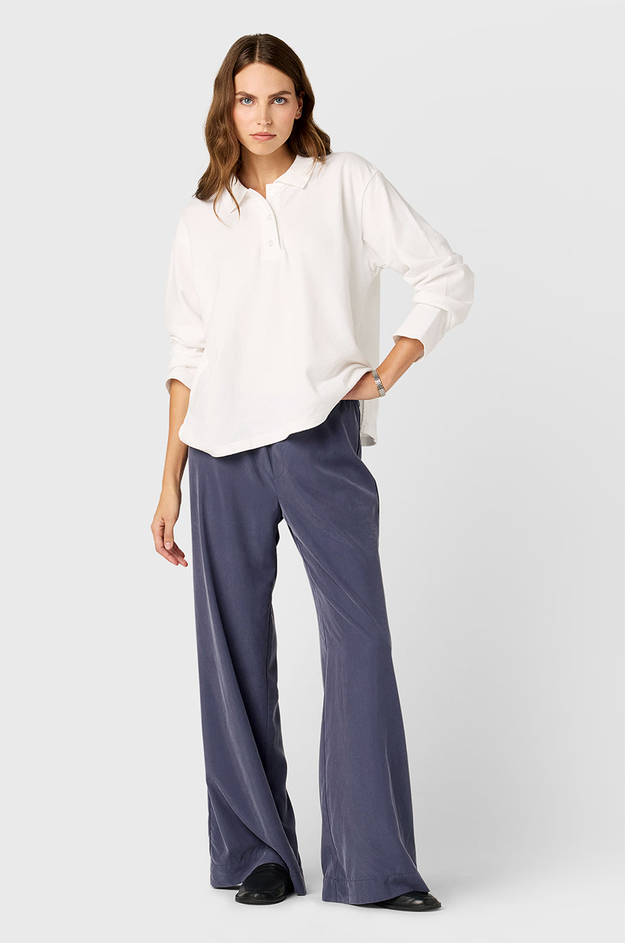 Model wearing the lady & the sailor BF Polo in White Cotton Twill and Silky Wide Leg Pants in Washed Steel.